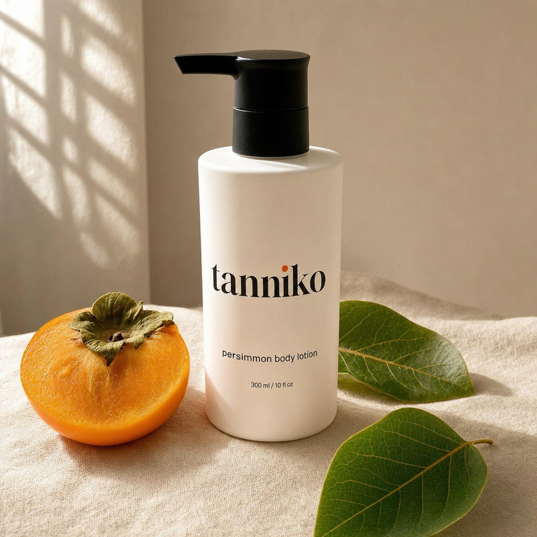Tanniko persimmon body lotion bottle beside a halved persimmon