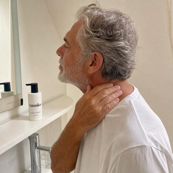 A man applying lotion to the back of his neck