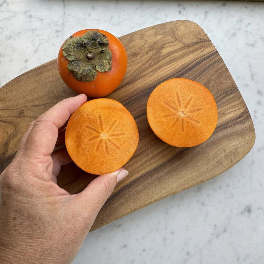 Fresh persimmons sliced on a wooden board